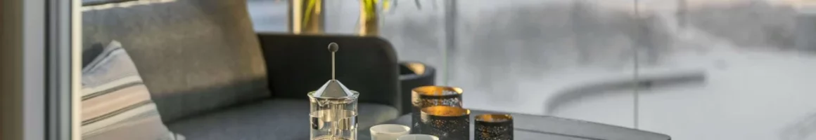 Coin salon dans une véranda avec cafetière à piston et tasses sur la table