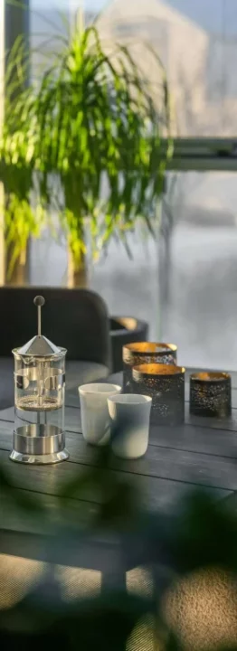 Coin salon dans une véranda avec cafetière à piston et tasses sur la table