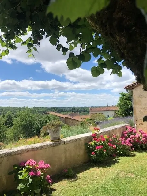 Vue sur la campagne du Périgord Vert avec hortensias roses au premier plan